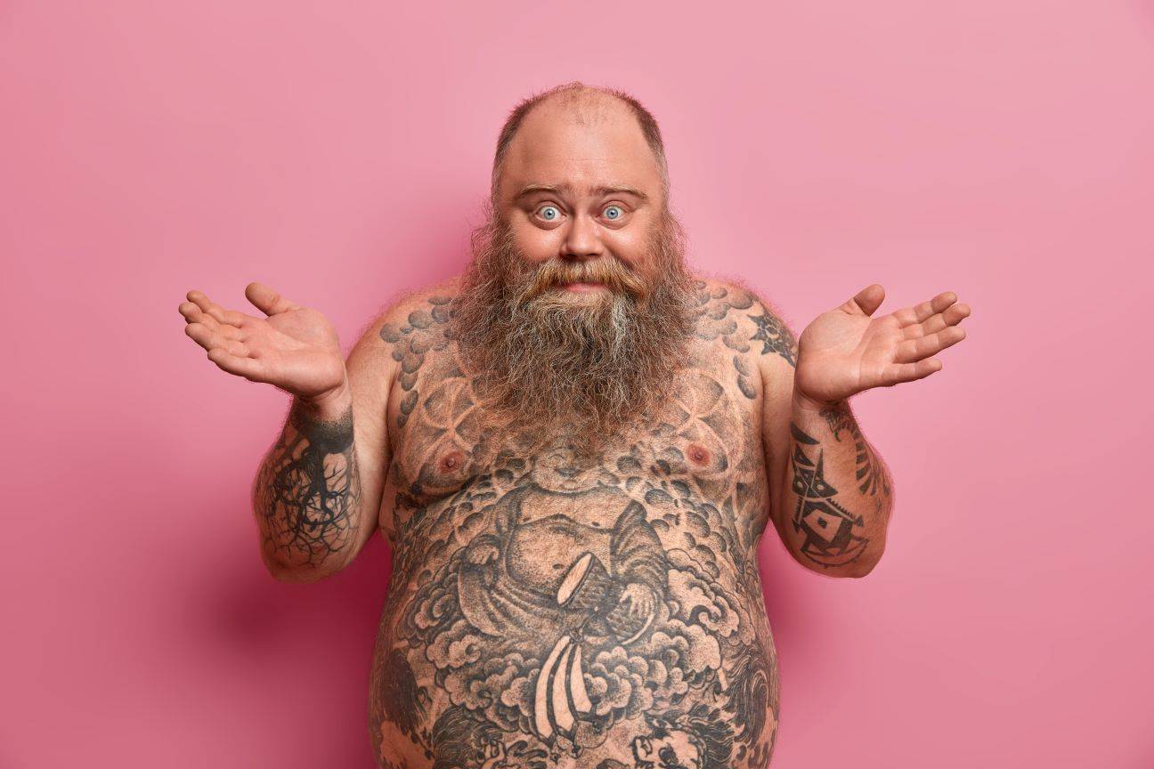 fat tattooed man smiling and looking confused